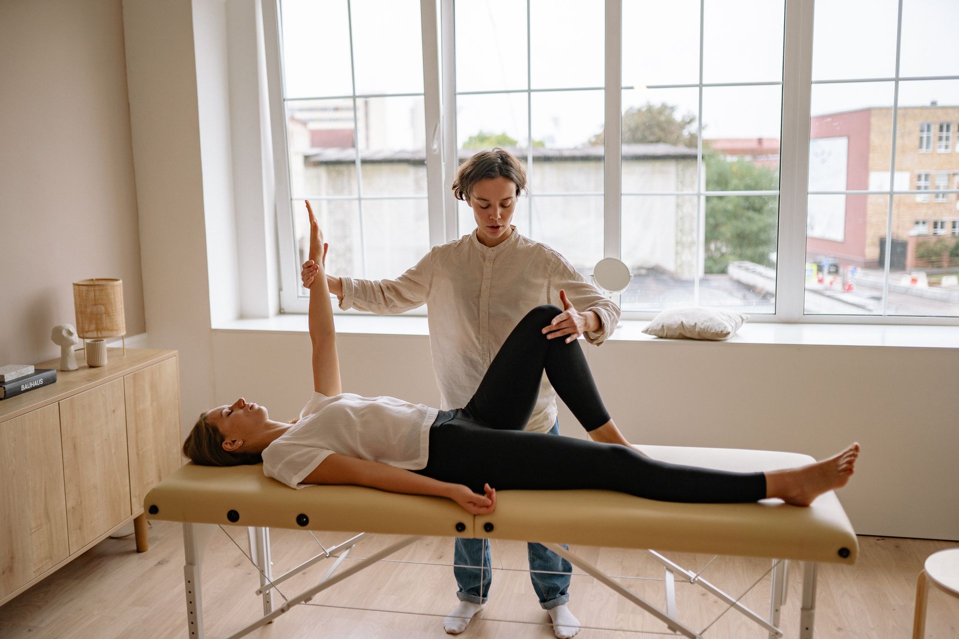 Physical therapist guiding a patient's stretch on a treatment table